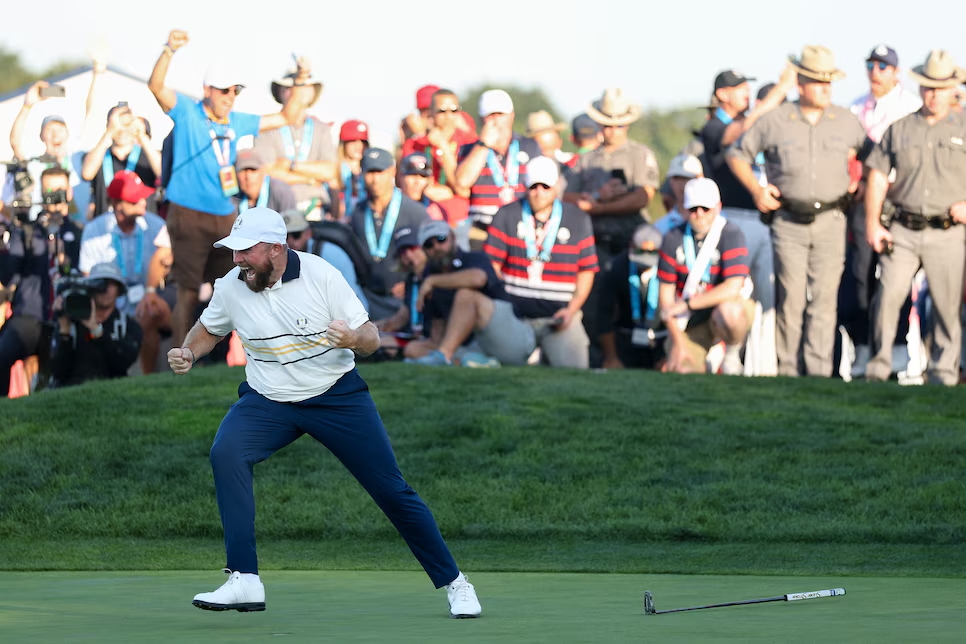 Golfer in white celebrating during match play with crowd behind